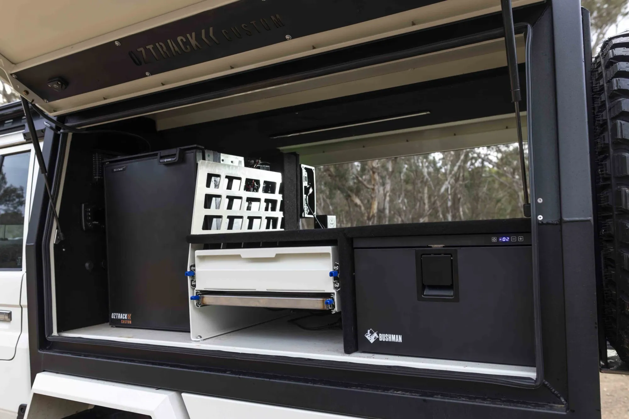 The open side of a black canopy on a 79 Series, fitted with a fridge slide and storage drawers
