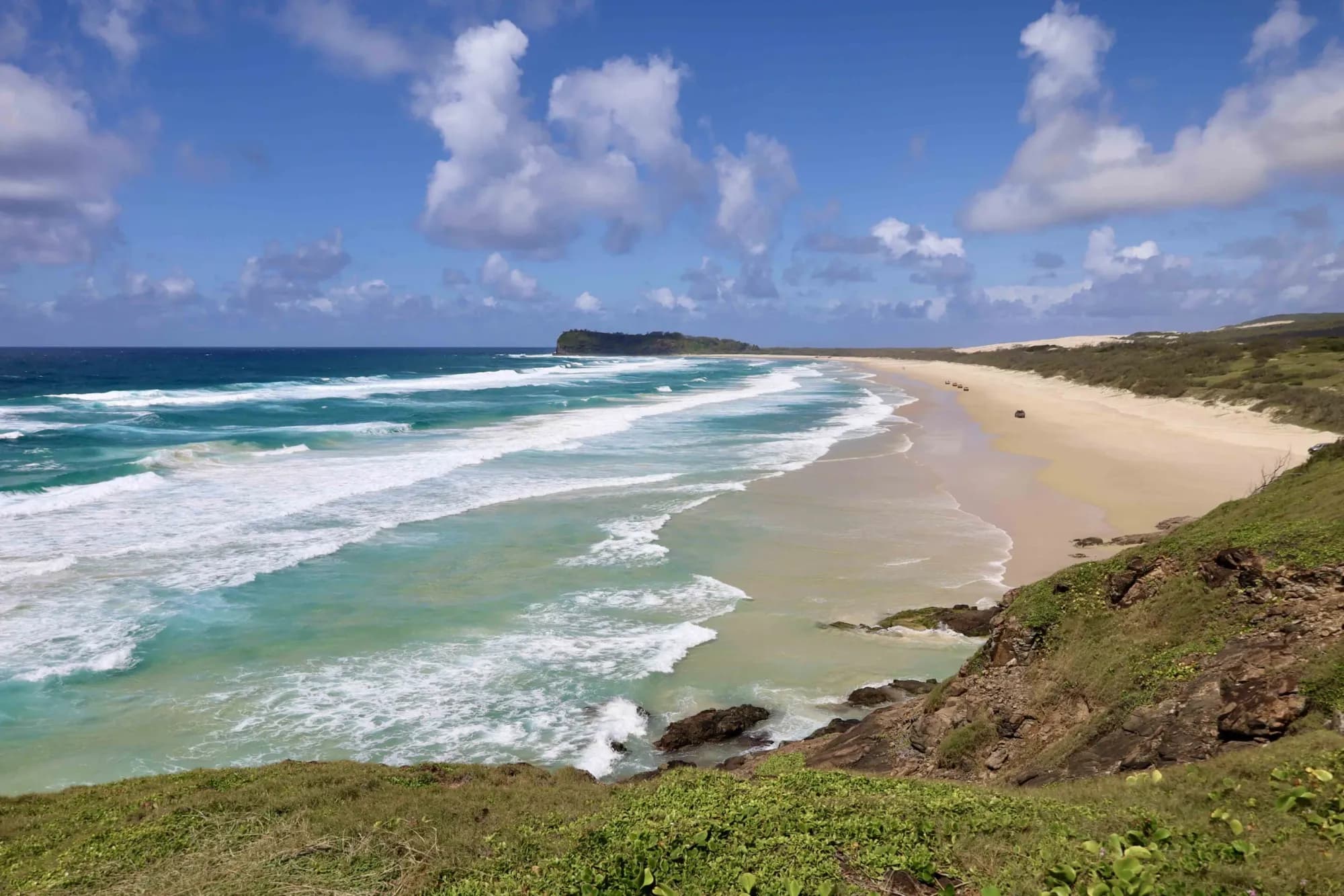 Drone view along the surf beach and headland of K’gari under a blue sky